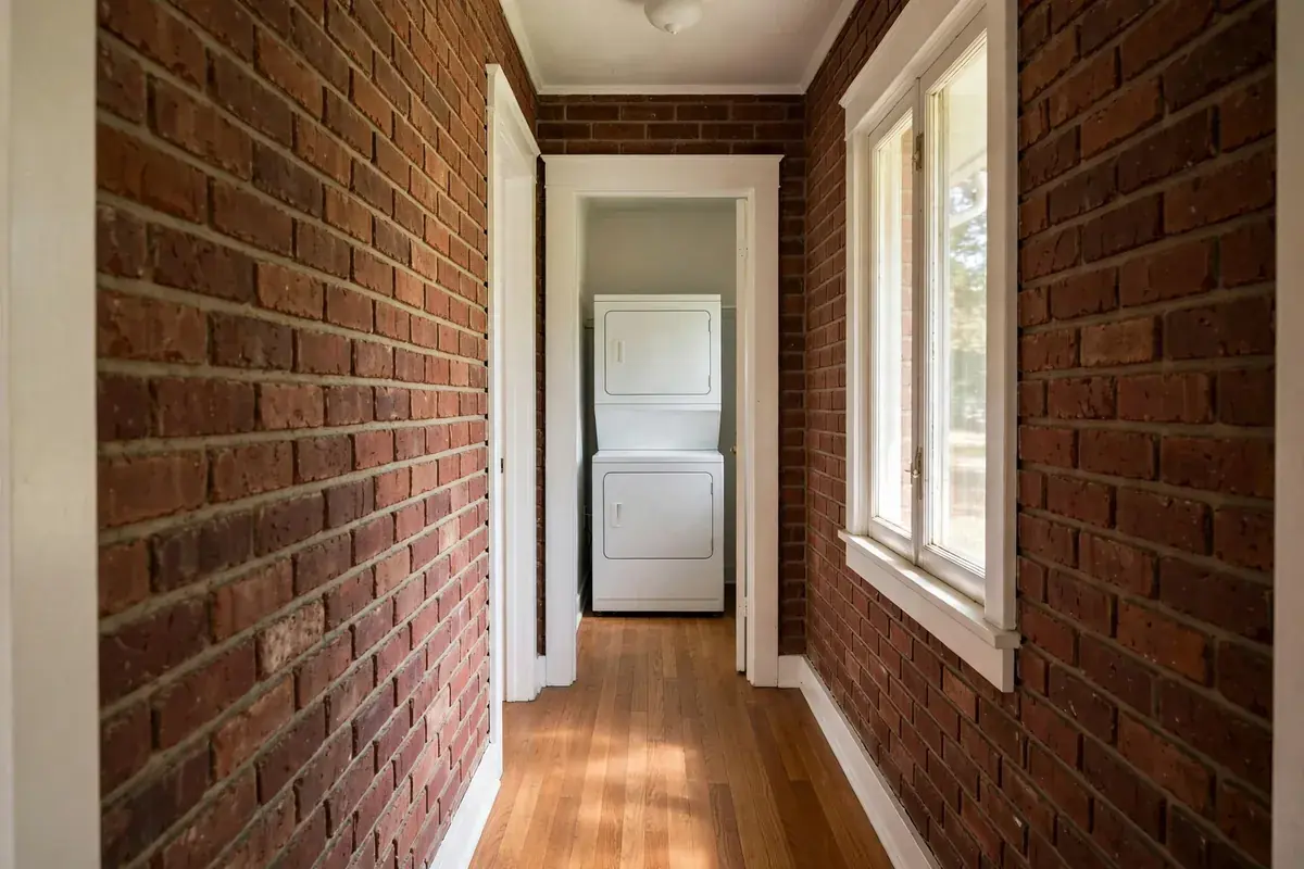 Laundry closet with a stacked washer and dryer at the end of a home hallway